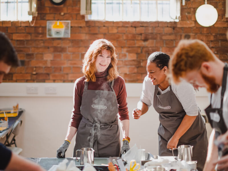 People smiling and wearing aprons at a candle making class.